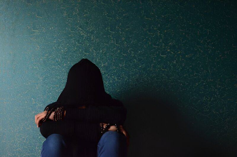 Troubled individual sits alone, visibly struggling, symbolizing the difficult battle against addiction