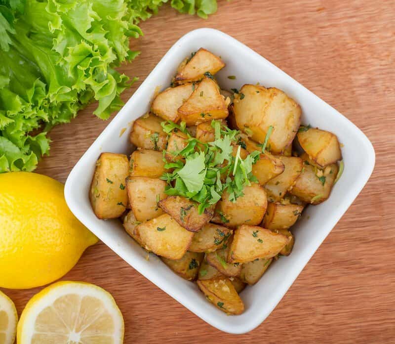 Spicy Lebanese batata harra served with lemon and lettuce.